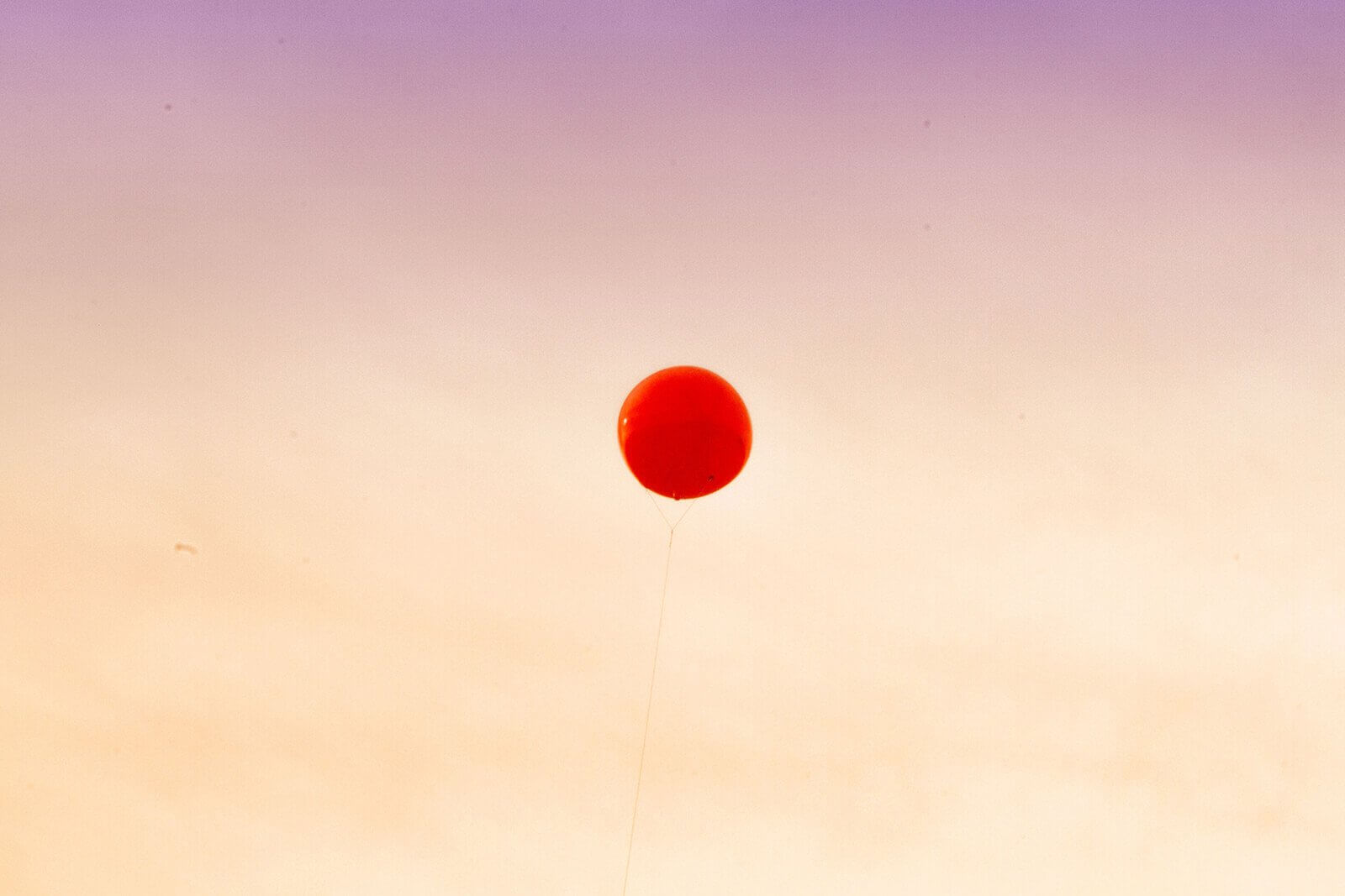 roter Ballon vor untergehendem Himmel